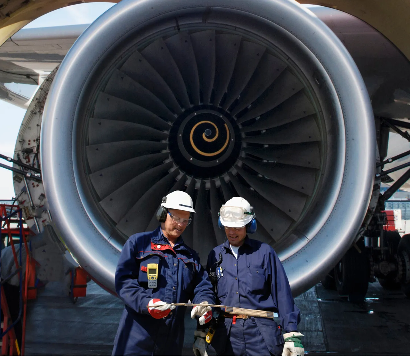 Two aviation technicians standing in front of an airplane turbine