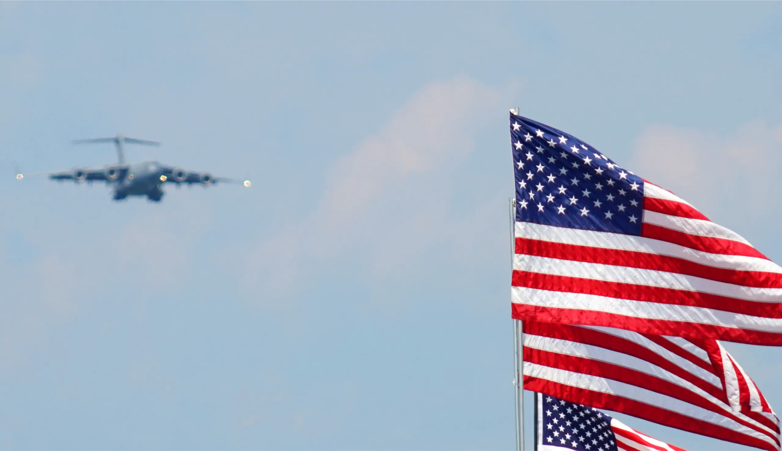 A military jet flying in the sky with three American flags