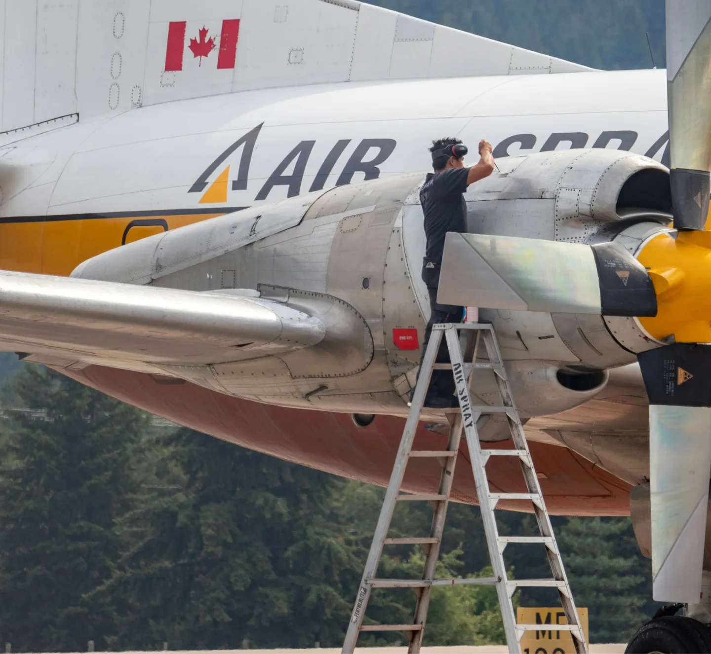 An airplane mechanic fixing the propellor of a commercial aircraft