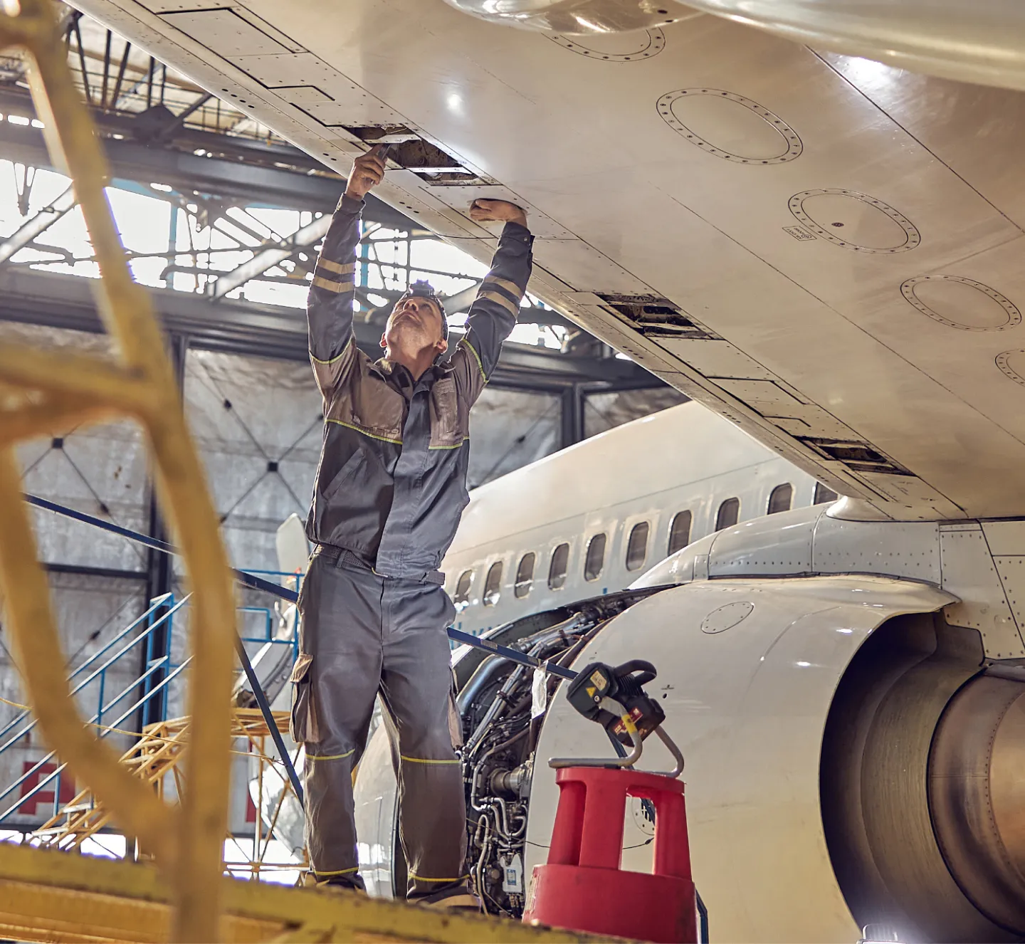 An aircraft mechanic fixing a part on a commercial airplane wing