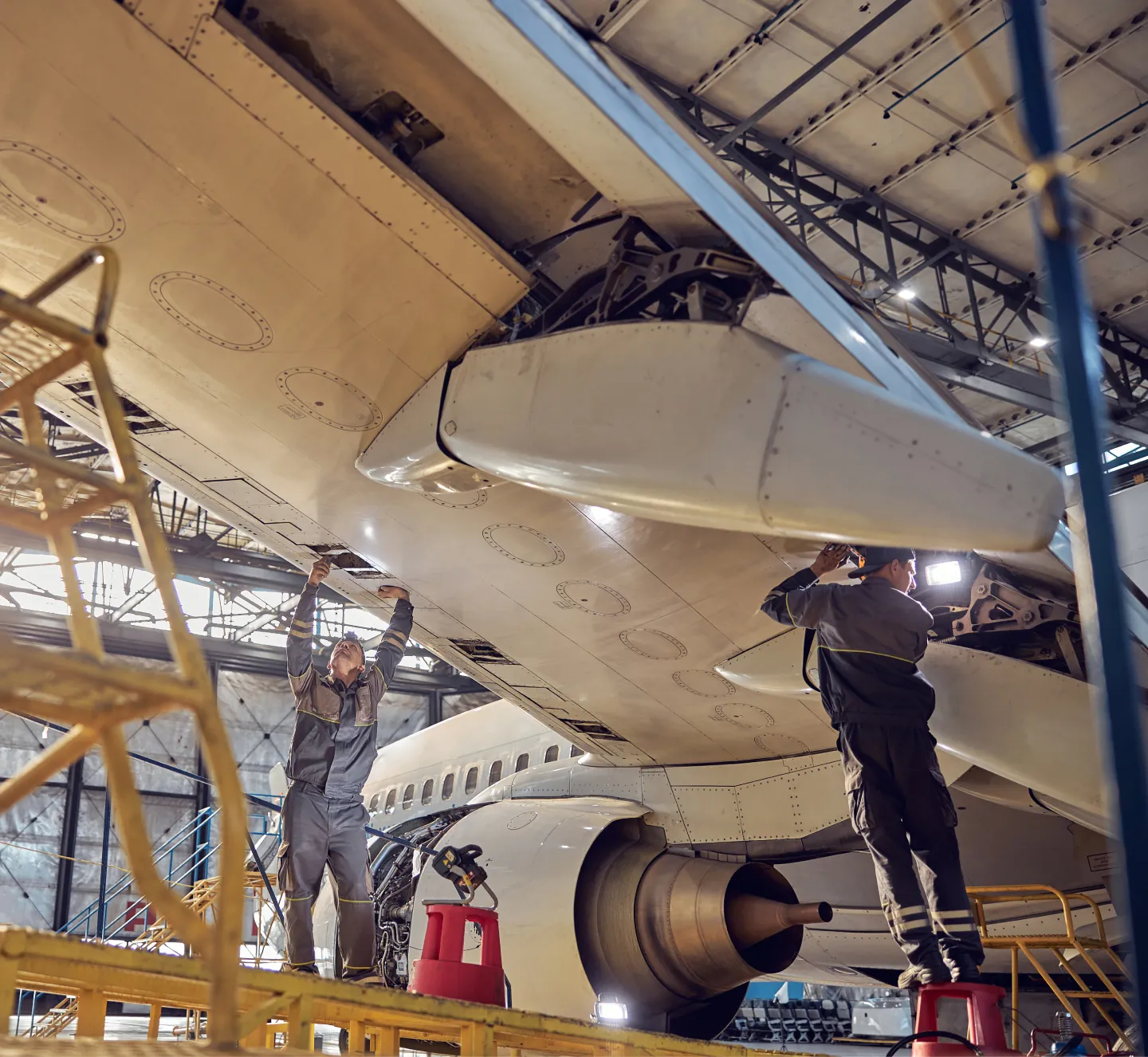 Two aviation mechanics working on repairing an airplane wing