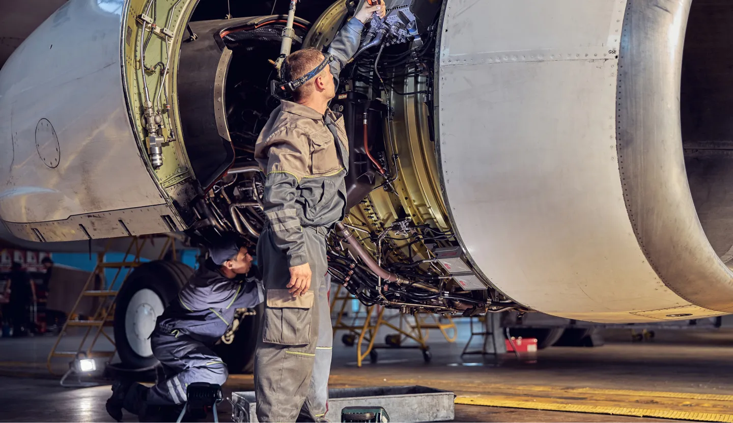 Two aircraft mechanics fixing an airplane engine